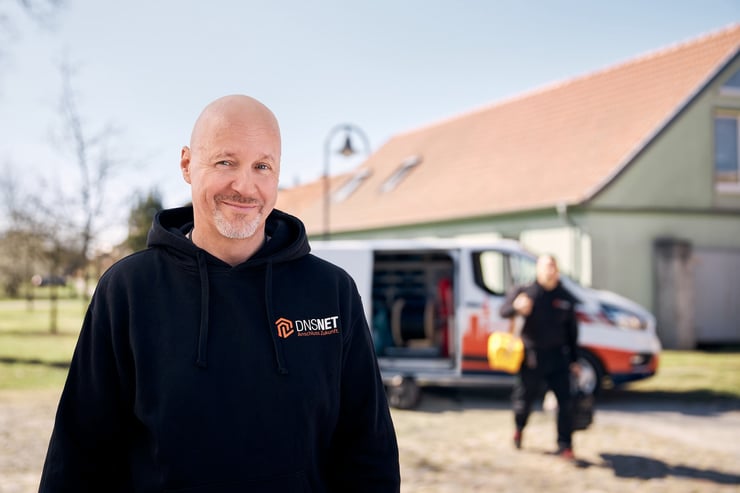 Mann im DNS-Sweater vor DNS Auto