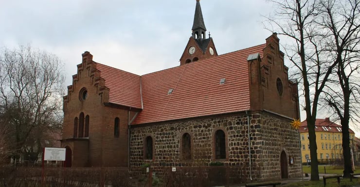 Dorfkirche in Berlin-Französisch Buchholz, historisches Backsteinbauwerk mit Uhrturm – gelegen in einem Ortsteil, in dem DNS:NET seit Frühjahr 2025 Glasfasertrassen verlegt und Netzverteiler errichtet.