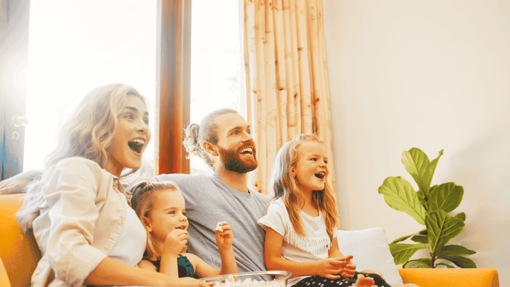 Familie mit zwei Kindern sitzt fröhlich auf dem Sofa und nutzt gemeinsam Highspeed-VDSL